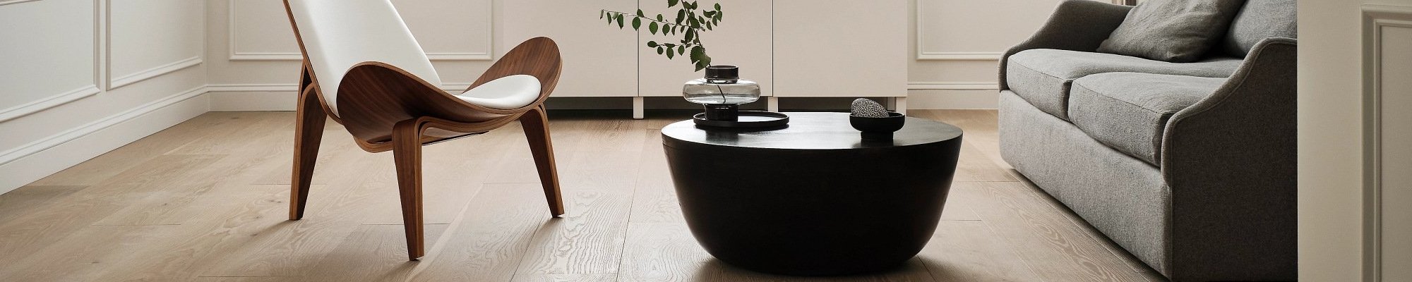 living room with hardwood floor and black coffee table with a plant on it in a glass vase from Carpet Innovations in Denver, CO